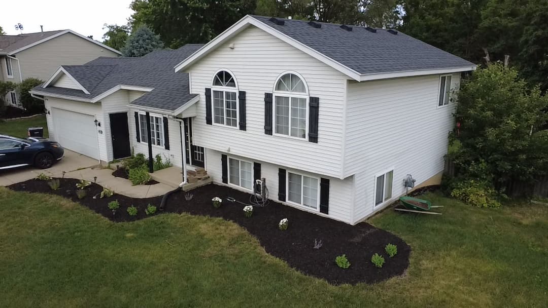 Aerial view of a modern two-story house with a landscaped yard and rectangular windows.