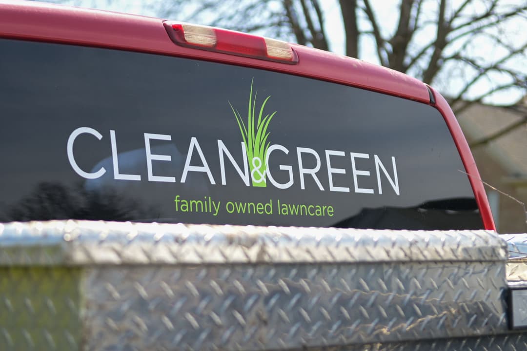 Clean & Green family-owned lawn care truck logo on a red pickup with a silver bed.