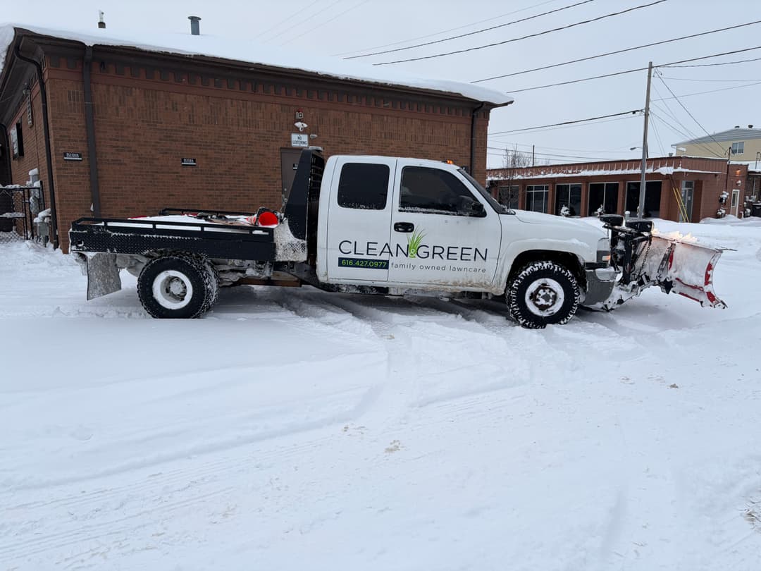 Snow plow truck from Clean and Green parked in snowy conditions, ready for winter service.