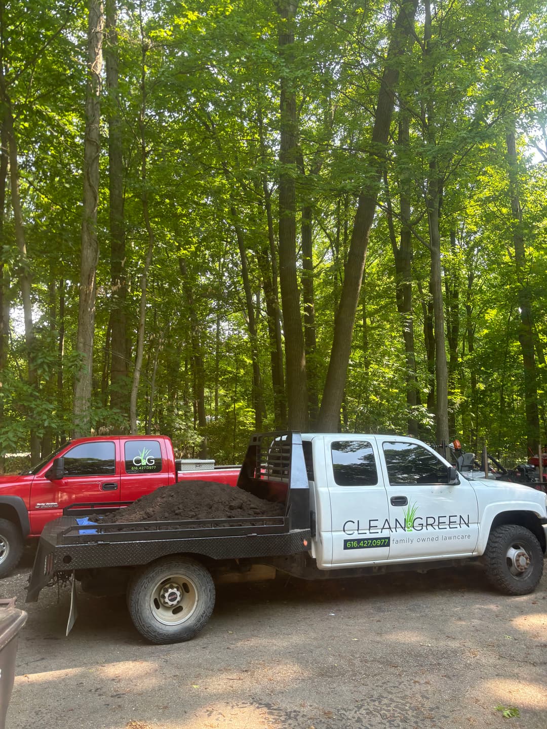 Pickup truck loaded with soil parked in a wooded area, promoting Clean Green services.